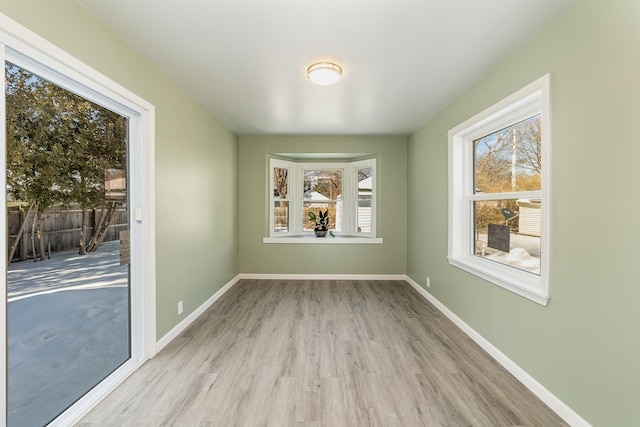 unfurnished dining area with light wood-type flooring and baseboards