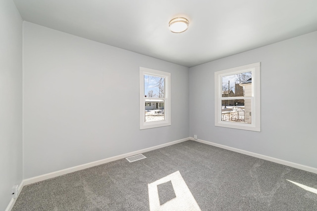 carpeted spare room with visible vents, plenty of natural light, and baseboards