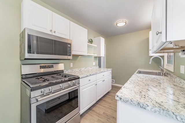 kitchen with stainless steel appliances, a sink, white cabinetry, light wood-type flooring, and open shelves