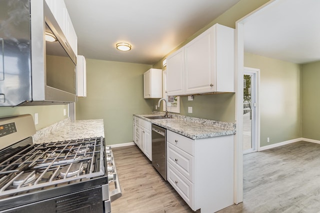 kitchen featuring light stone counters, stainless steel appliances, light wood-style floors, white cabinetry, and a sink