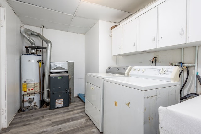 clothes washing area featuring water heater, cabinet space, light wood-style floors, washing machine and dryer, and a sink