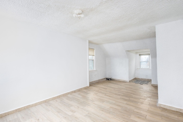 spare room featuring a healthy amount of sunlight, light wood-style flooring, and a textured ceiling