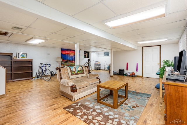 living area featuring light wood finished floors, a drop ceiling, and visible vents