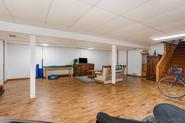 workout area featuring baseboards, visible vents, a drop ceiling, and wood finished floors