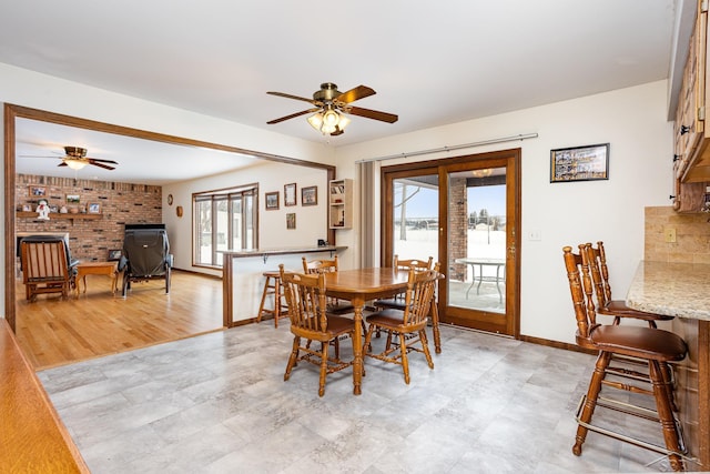 dining room with ceiling fan, brick wall, and baseboards