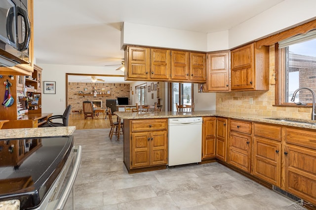 kitchen with brown cabinets, dishwasher, a peninsula, and a sink