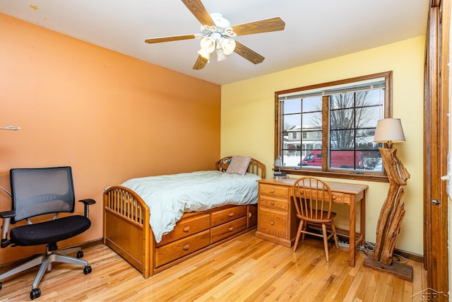 bedroom with light wood finished floors, a ceiling fan, and baseboards