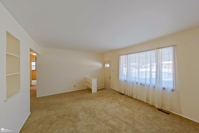 spare room featuring light carpet and visible vents