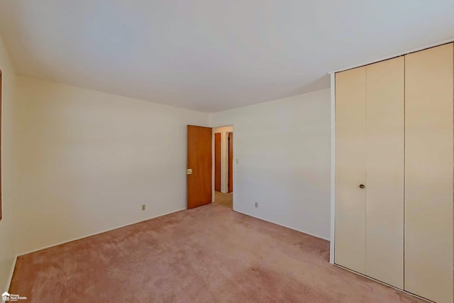 unfurnished bedroom featuring a closet and light colored carpet