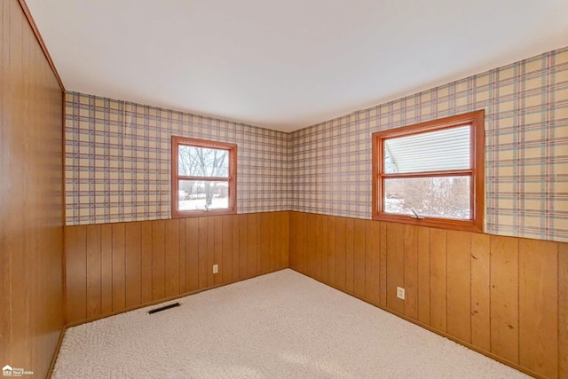 spare room with carpet, wainscoting, visible vents, and wallpapered walls