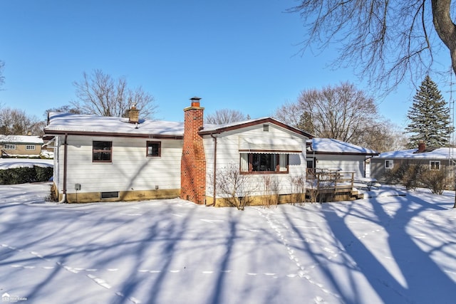 snow covered back of property with a chimney