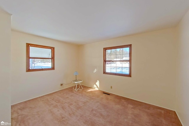 spare room featuring visible vents and light colored carpet