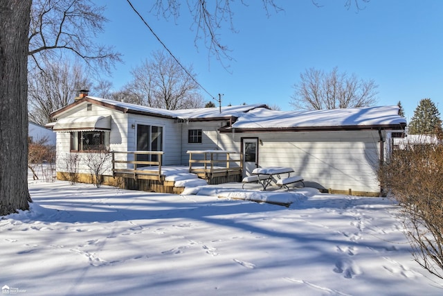 snow covered rear of property with a deck