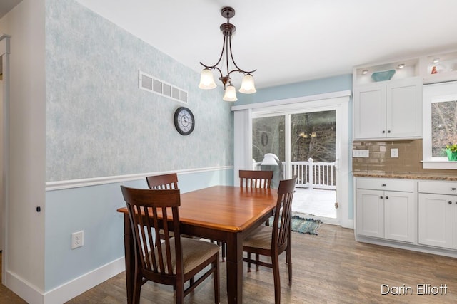 dining area featuring visible vents, dark wood finished floors, baseboards, and an inviting chandelier