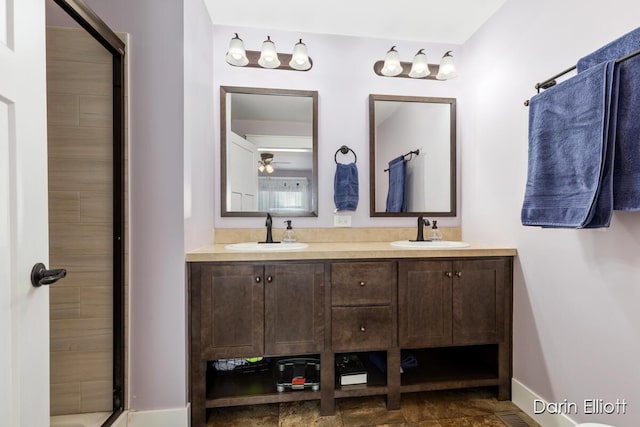 bathroom featuring a shower, a sink, baseboards, and double vanity