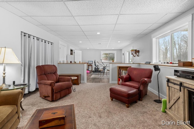 carpeted living area with a paneled ceiling, baseboards, and recessed lighting