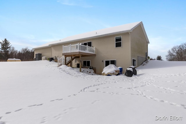 snow covered house featuring stairway, a deck, and a garage