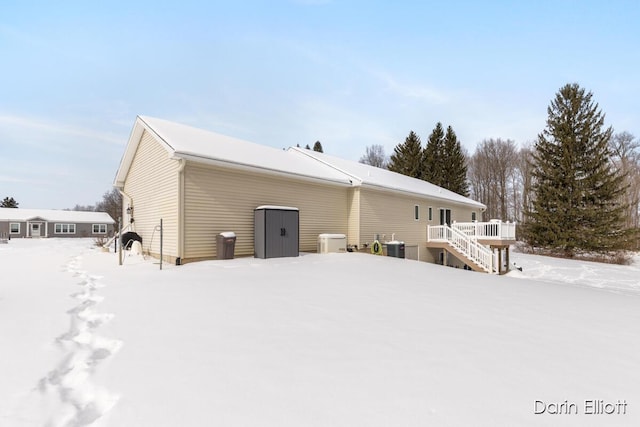 snow covered rear of property featuring stairway, central AC unit, and a deck