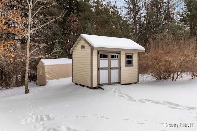 snow covered structure with an outdoor structure and a storage unit