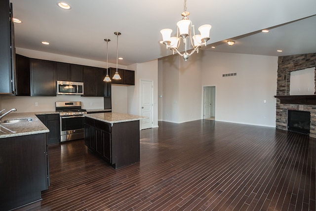 kitchen with a kitchen island, stainless steel appliances, a sink, and decorative light fixtures