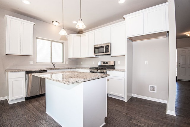 kitchen with a center island, pendant lighting, appliances with stainless steel finishes, white cabinetry, and a sink