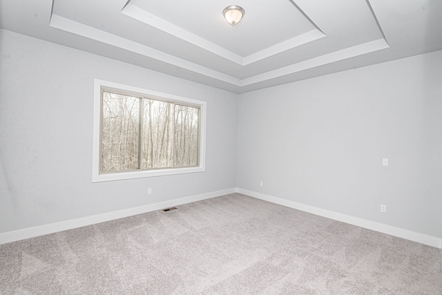 unfurnished room with visible vents, baseboards, a tray ceiling, and carpet flooring