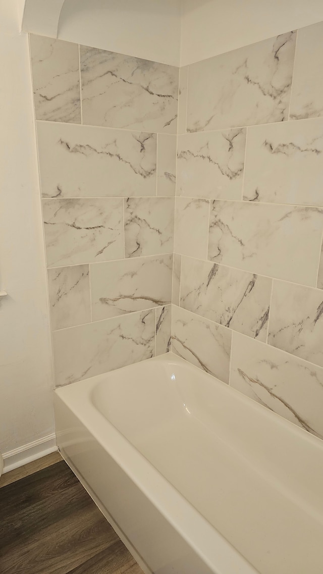 full bath featuring a washtub, baseboards, and wood finished floors