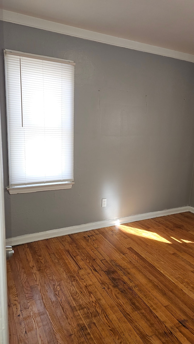 unfurnished room featuring crown molding, baseboards, and wood finished floors