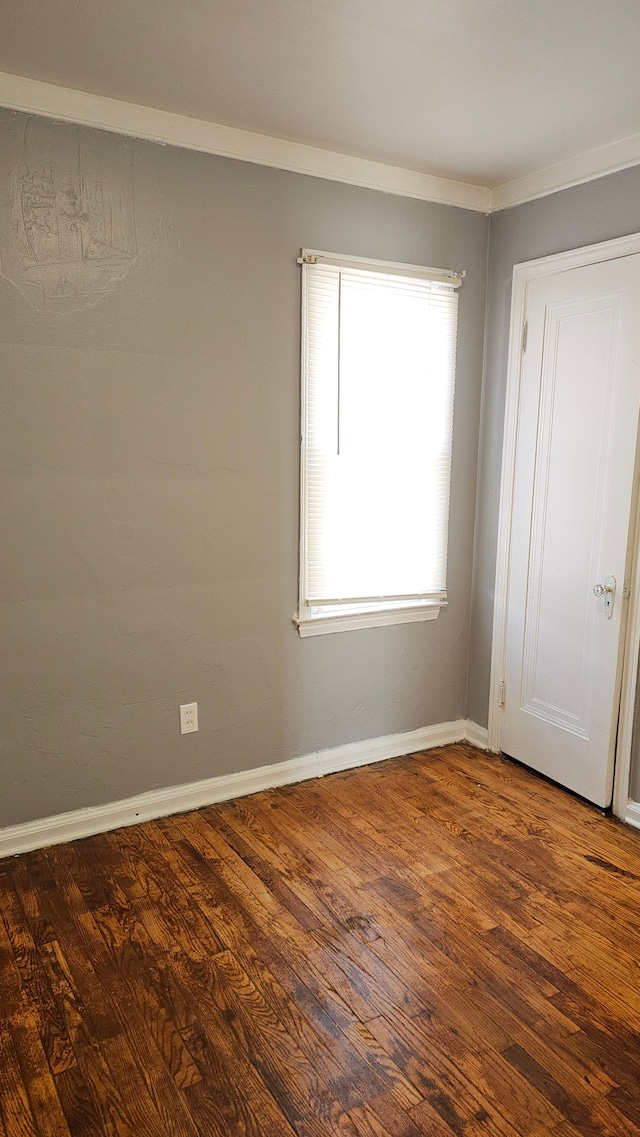 empty room featuring dark wood-style floors and baseboards