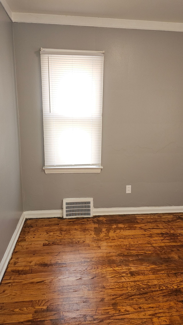 empty room featuring visible vents, dark wood finished floors, and baseboards