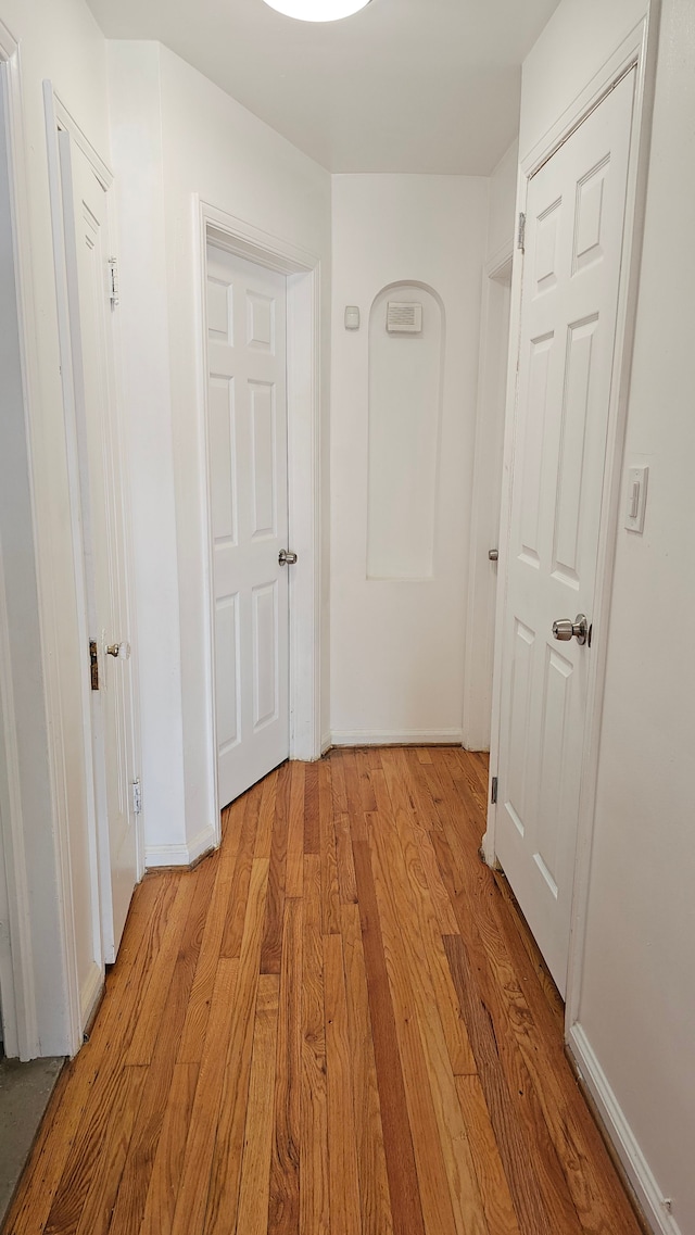 corridor featuring light wood-type flooring and baseboards