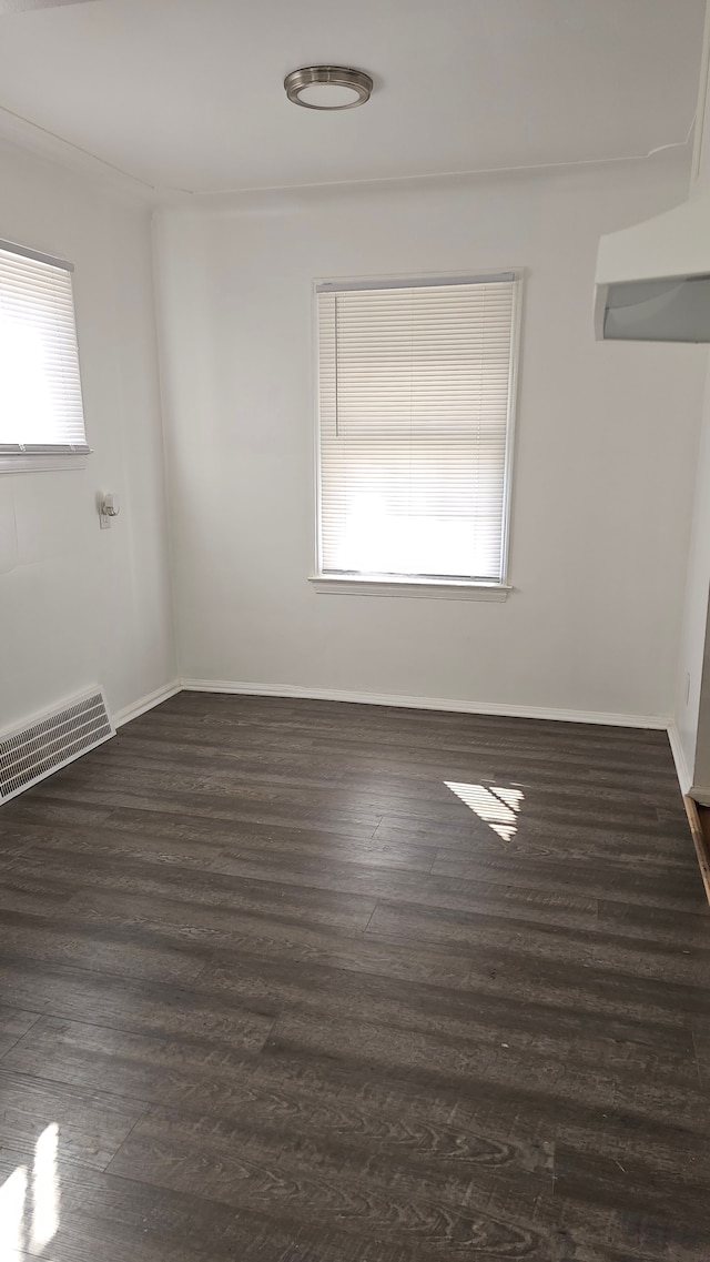 spare room featuring dark wood-style floors, baseboards, and visible vents