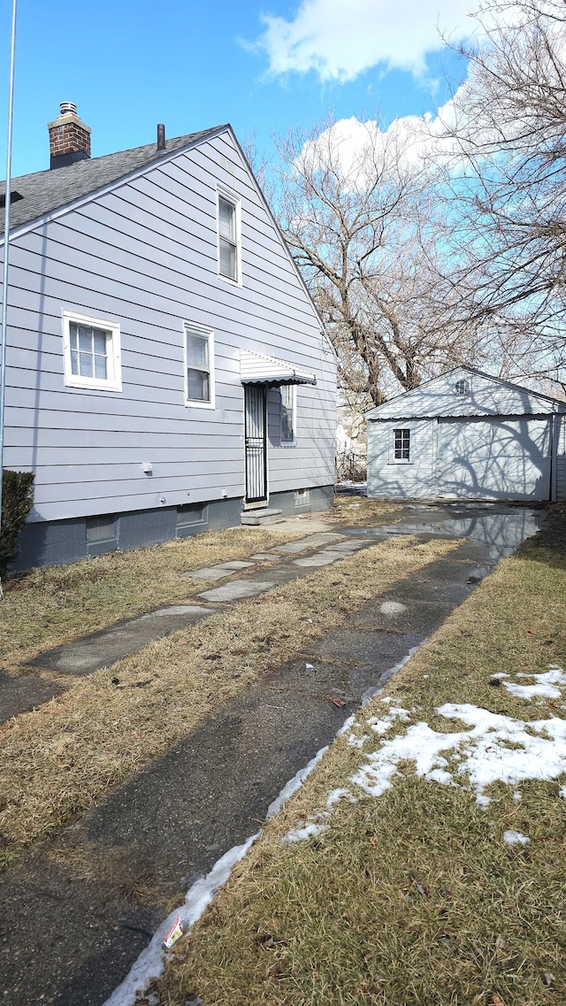 back of property with an outbuilding, a chimney, and entry steps