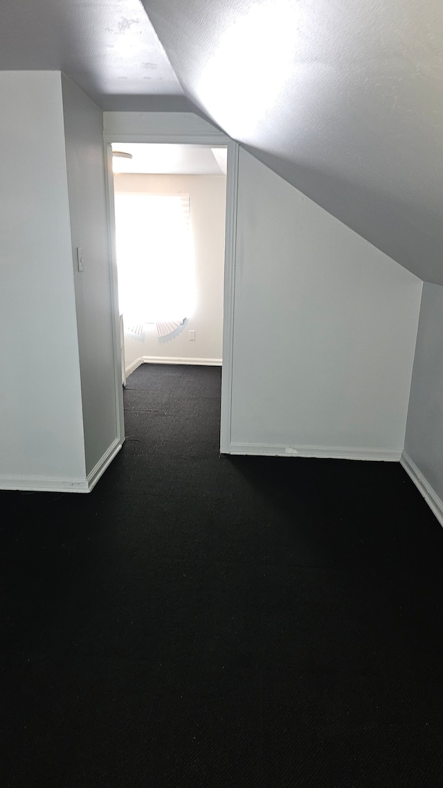 bonus room with baseboards, vaulted ceiling, and a textured ceiling