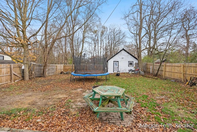 view of yard with a trampoline, an outdoor structure, and a fenced backyard