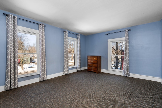 carpeted empty room featuring a wealth of natural light and baseboards