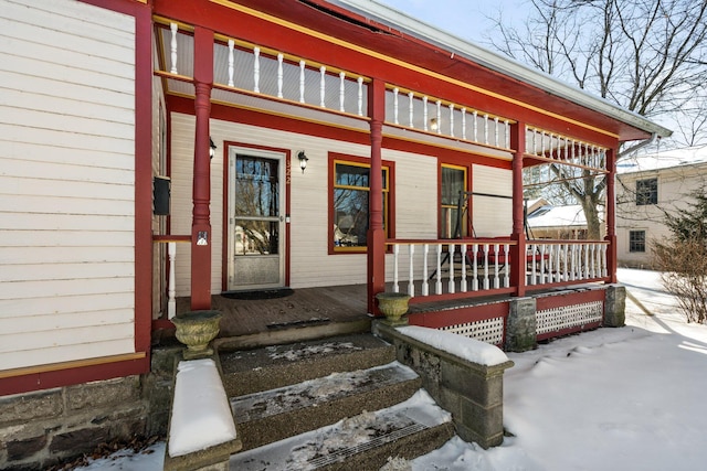 snow covered property entrance with covered porch