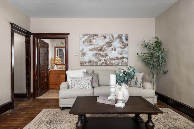 living room featuring a textured ceiling, baseboards, and dark wood-type flooring