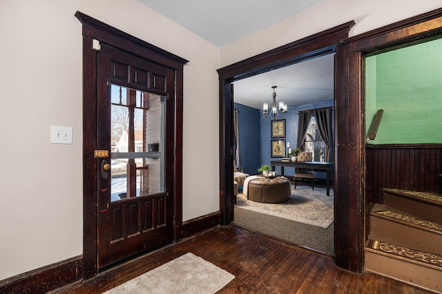 foyer featuring a chandelier, dark wood-type flooring, and baseboards