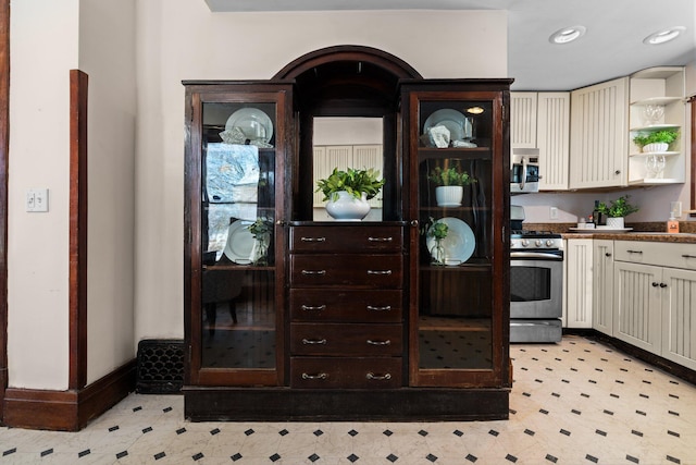 kitchen featuring cream cabinetry, open shelves, stainless steel appliances, recessed lighting, and glass insert cabinets