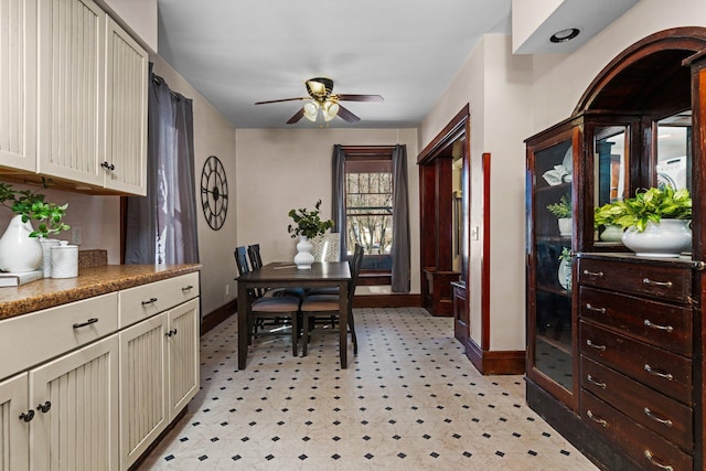 dining space featuring ceiling fan, light floors, and baseboards