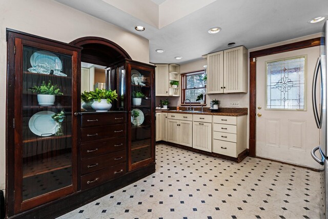 kitchen featuring dark countertops, cream cabinetry, a sink, and recessed lighting