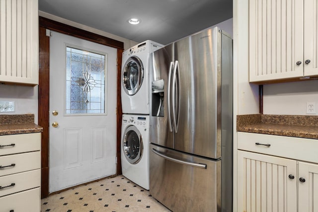 clothes washing area featuring stacked washing maching and dryer, laundry area, and light floors