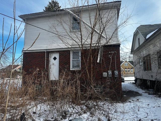 view of snowy exterior featuring brick siding