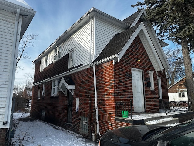 snow covered property with brick siding