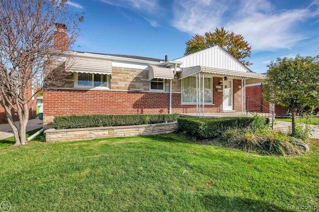 view of front of home with a front yard, a chimney, and brick siding