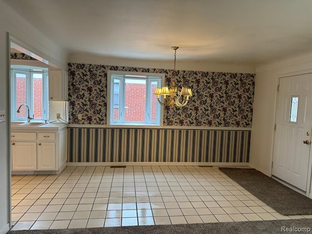 unfurnished dining area with light tile patterned floors, wainscoting, a sink, and wallpapered walls