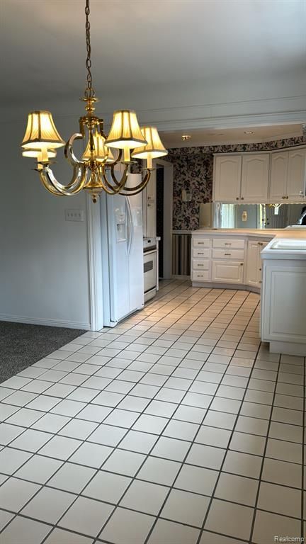 kitchen featuring a chandelier, light tile patterned flooring, white cabinets, light countertops, and electric range oven