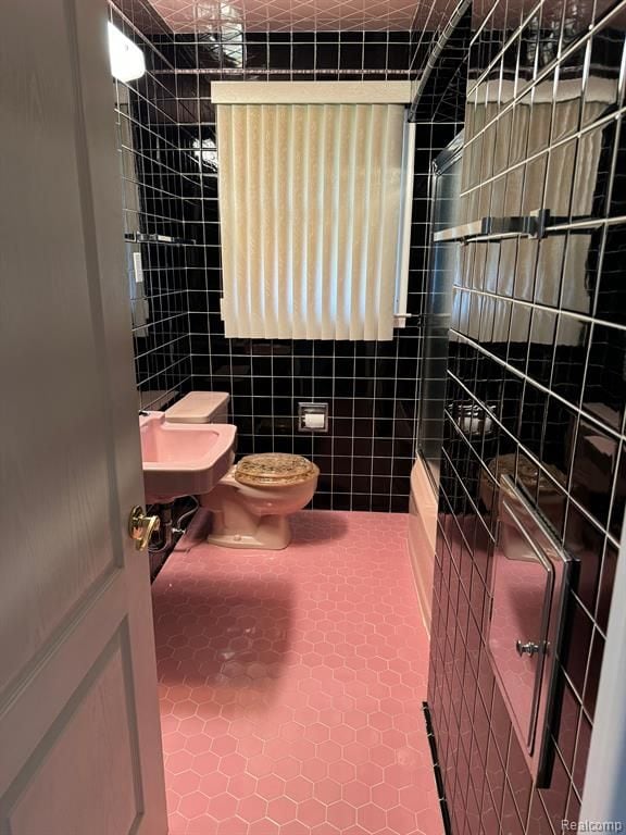 full bath featuring a sink, tile walls, toilet, and tile patterned floors