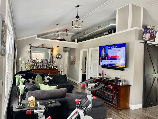 living room featuring lofted ceiling, a barn door, wood finished floors, and baseboards